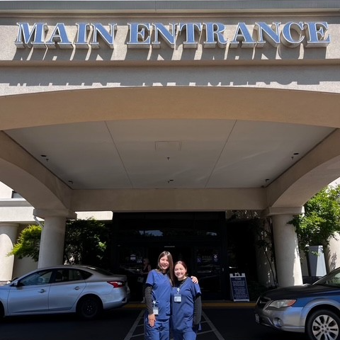 BCCS medical pathway students in front of hospital main entrance wearing scrubs.